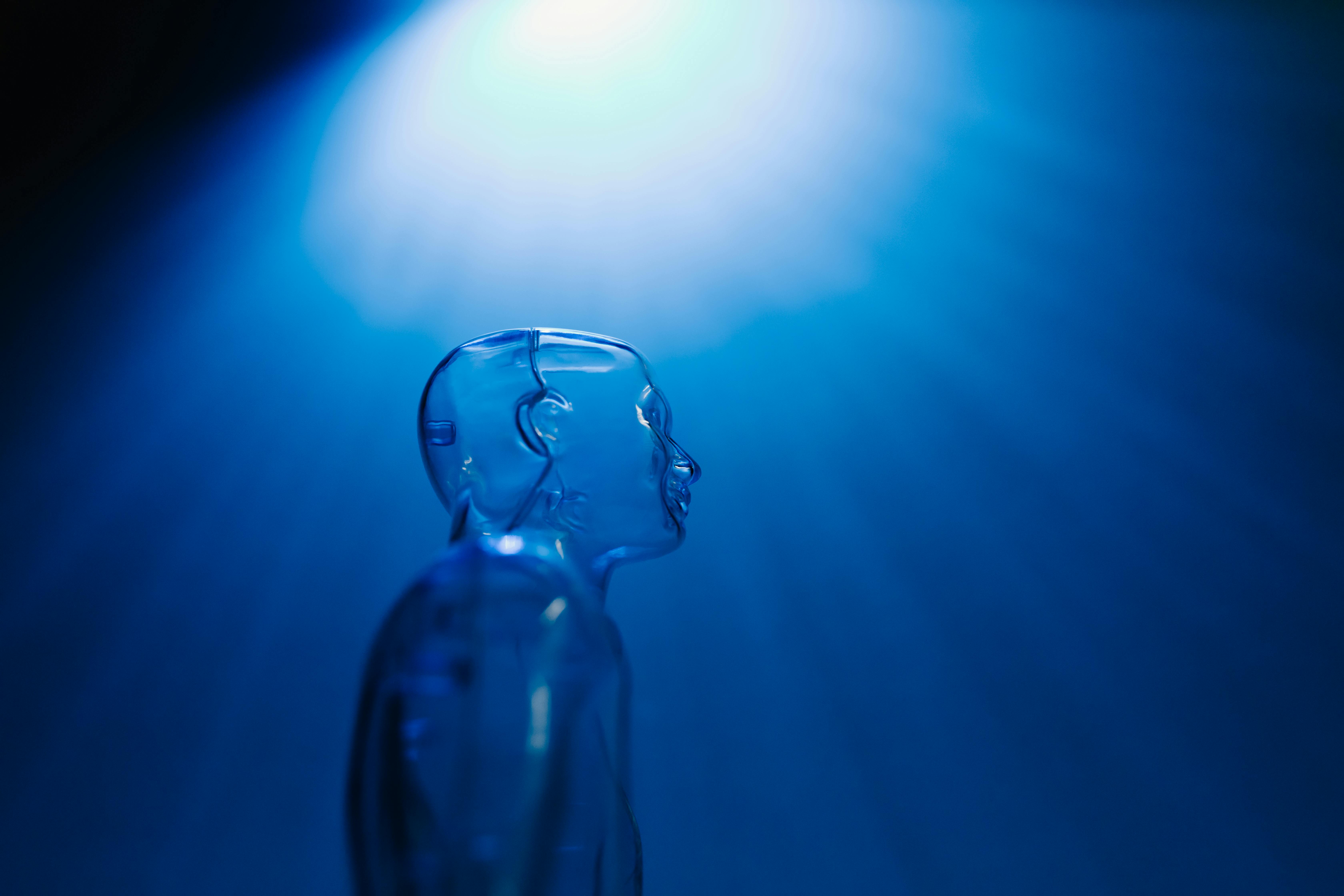 Transparent robotic figure illuminated by blue light, symbolizing AI and futuristic technology.